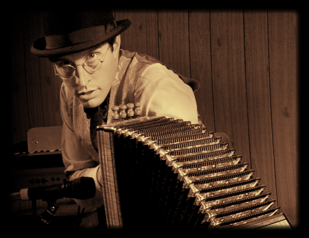 Sepia image of Roger Dallaire, French-Canadian storyteller, musician, actor, puppeteer and folklorist. Dallaire looks at camera in a top-hat and round glasses behind an accordion.